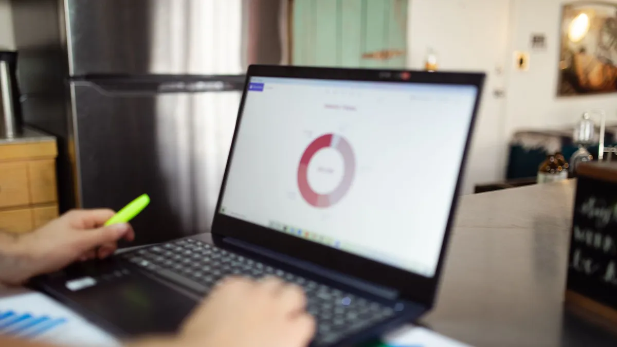 Person analyzing business data on a laptop in a modern indoor setting.