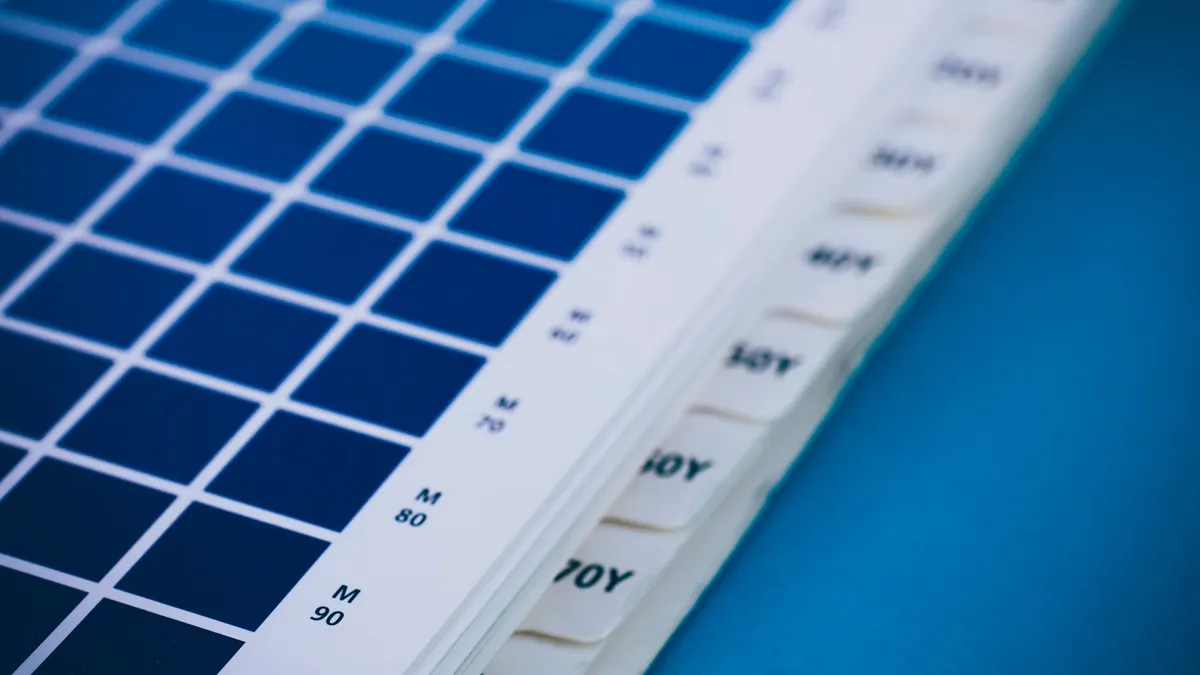 Close-up of a blue color swatch book showing different shades and codes.