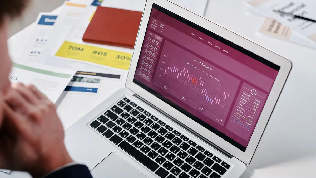 Businessperson reviewing data analytics on a laptop screen in an office setting.