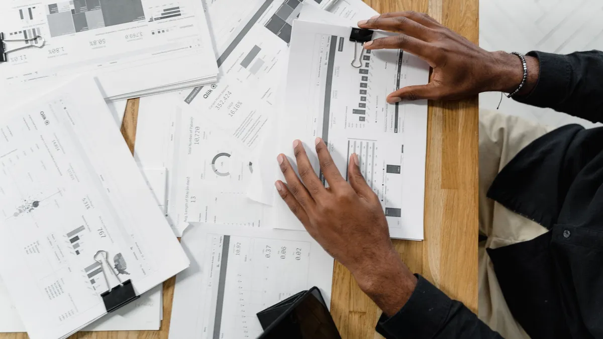 Top view of a professional reviewing financial documents at a wooden workspace.