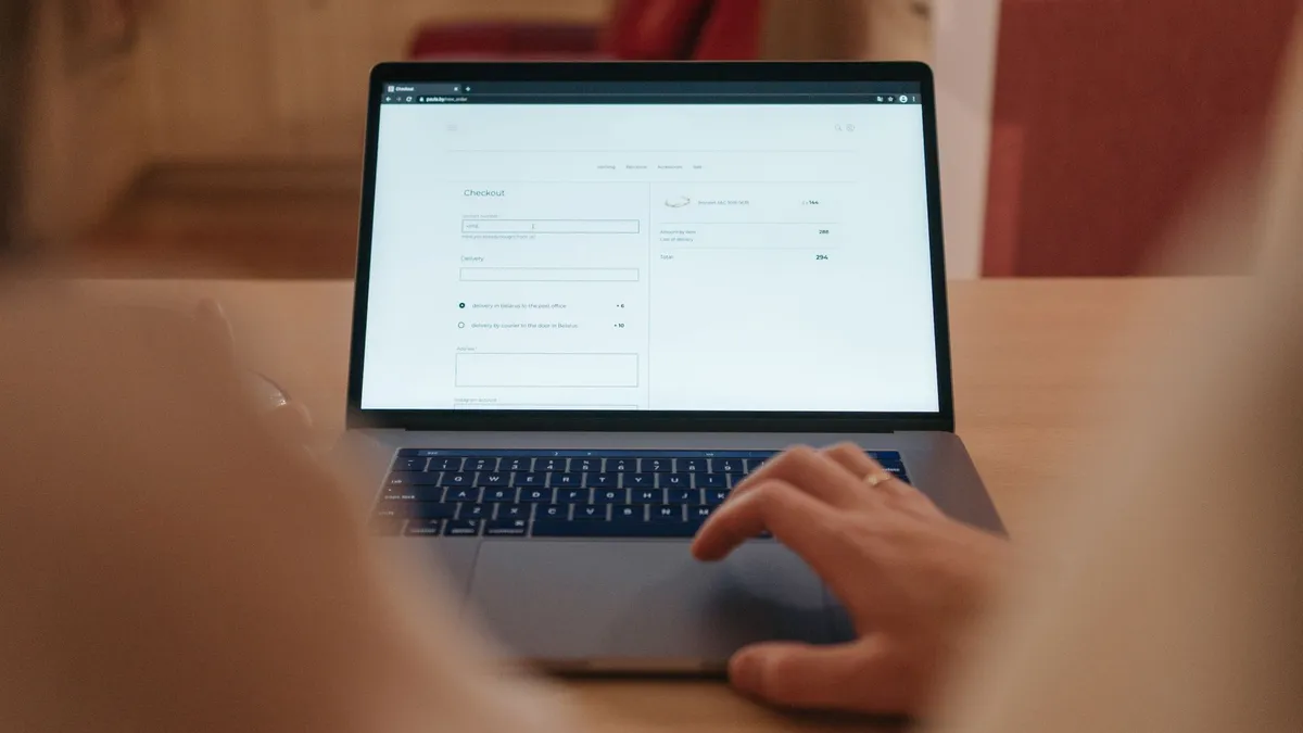 Close-up of a person navigating online checkout on a laptop screen in a cozy indoor setting.