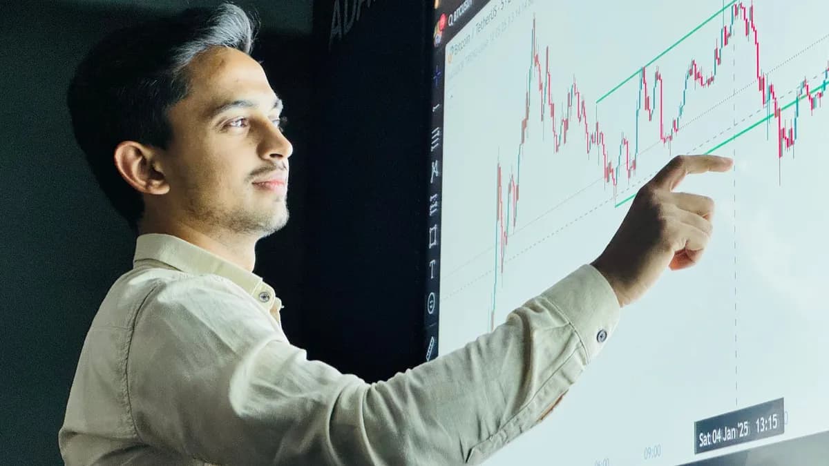 Man analyzing stock market graph on a digital board with a focused expression.