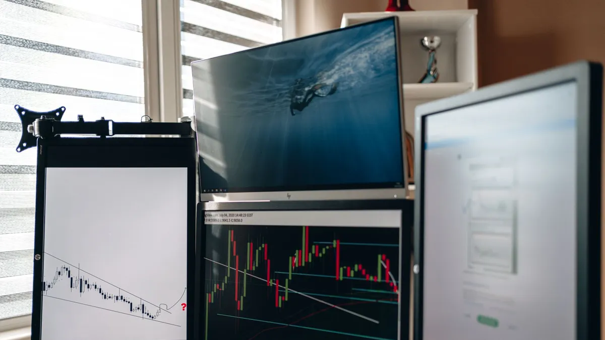 A home office setup featuring multiple monitors displaying trading charts and data analysis.