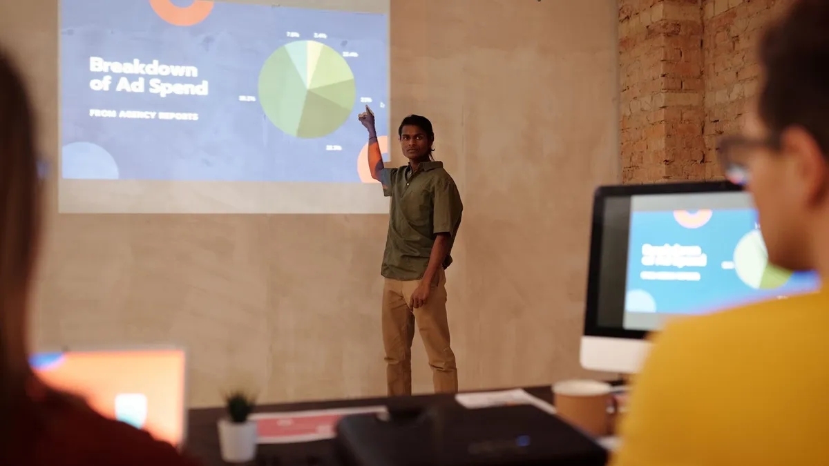 Young man delivering a business presentation on ad spend with charts and graphs in a modern office setting.