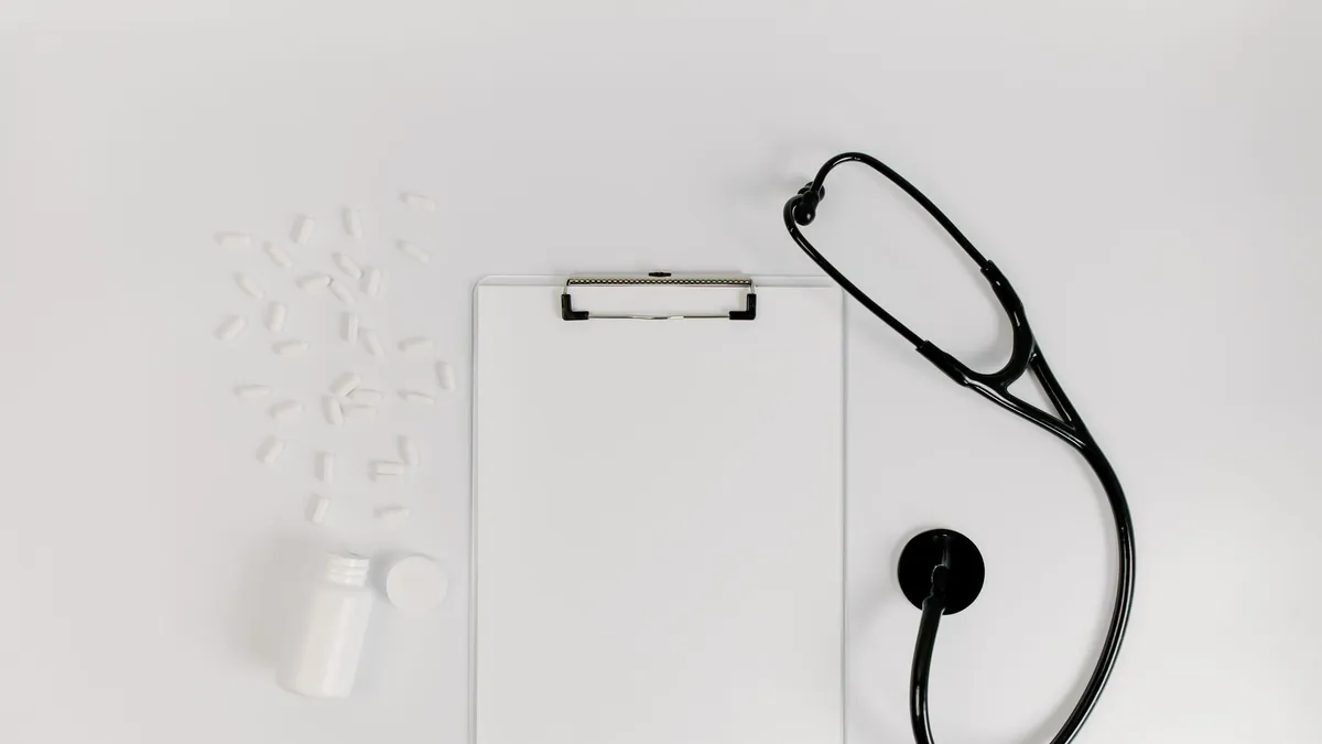 Flat lay of clipboard, pills, and stethoscope for medical use.