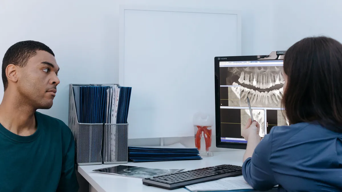 Patient consulting a dentist reviewing dental X-ray in a clinic setting.