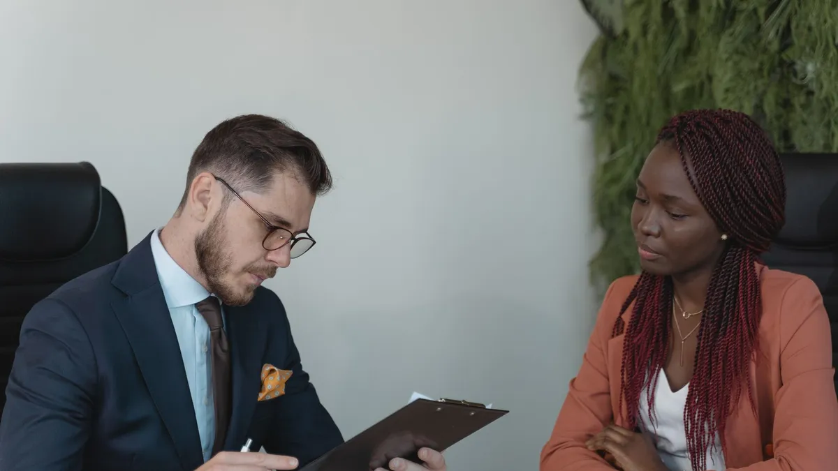 A man and woman engaging in a job interview in a modern office setting.