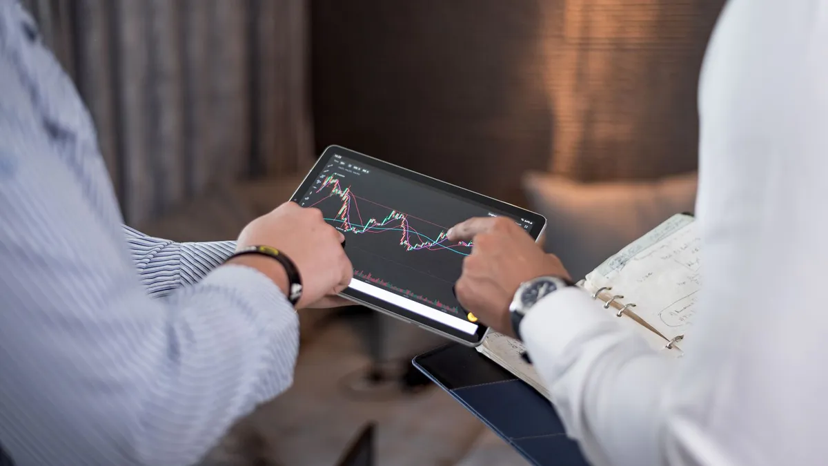 Close-up of business professionals discussing financial data on a digital tablet.