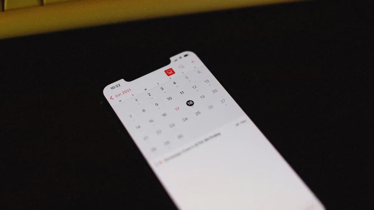 Smartphone with illuminated calendar app screen on a dark background, June 2021 visible.