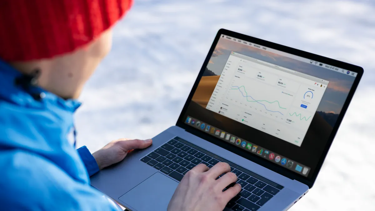 Person working on a laptop analyzing charts in an outdoor setting during winter.