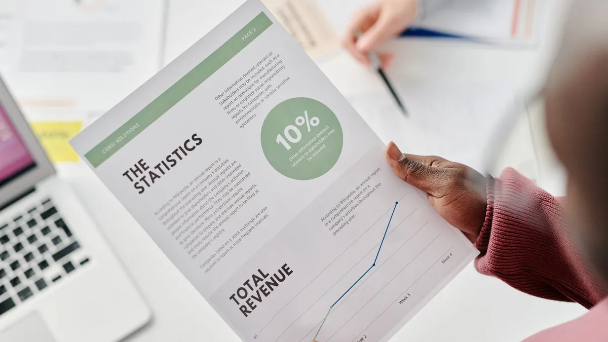 Hands holding a statistical report during a business meeting. Includes revenue graphs and analysis.