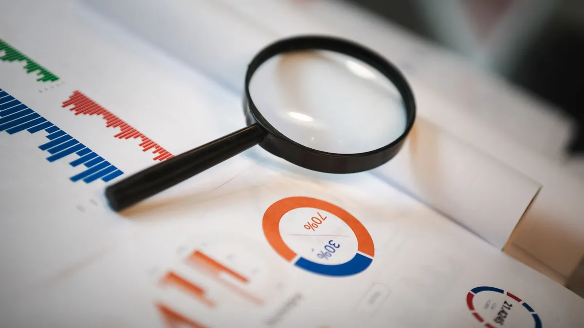 An image showcasing a magnifying glass placed on financial graphs and charts depicting statistical data.