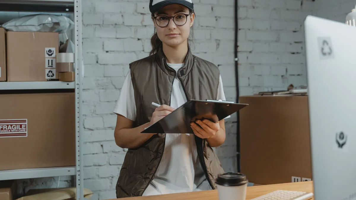 Young woman with clipboard in a warehouse, managing inventory with precision.