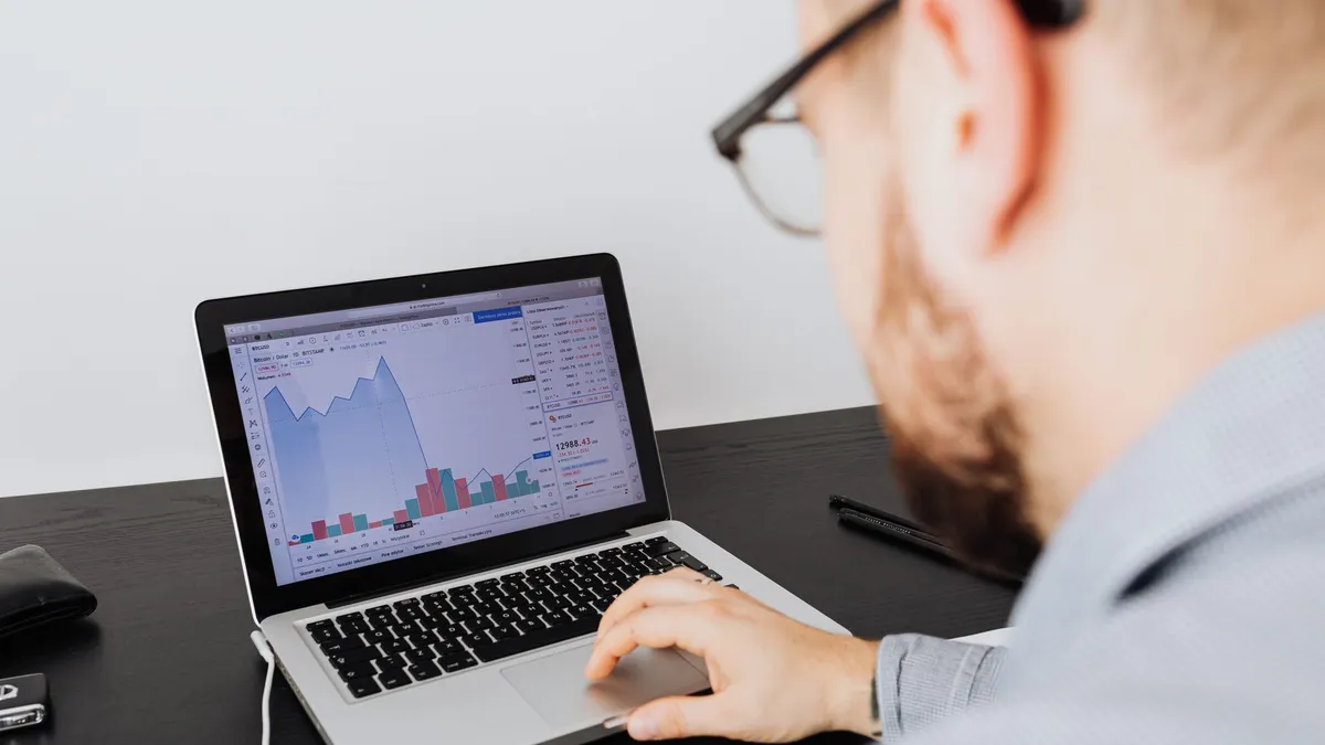 Man working on a laptop analyzing business data and financial graphs indoors.