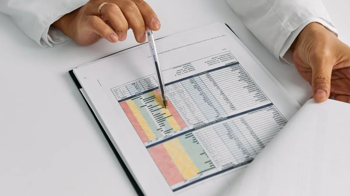 Doctor hands examining and pointing at medical charts in a close-up view.