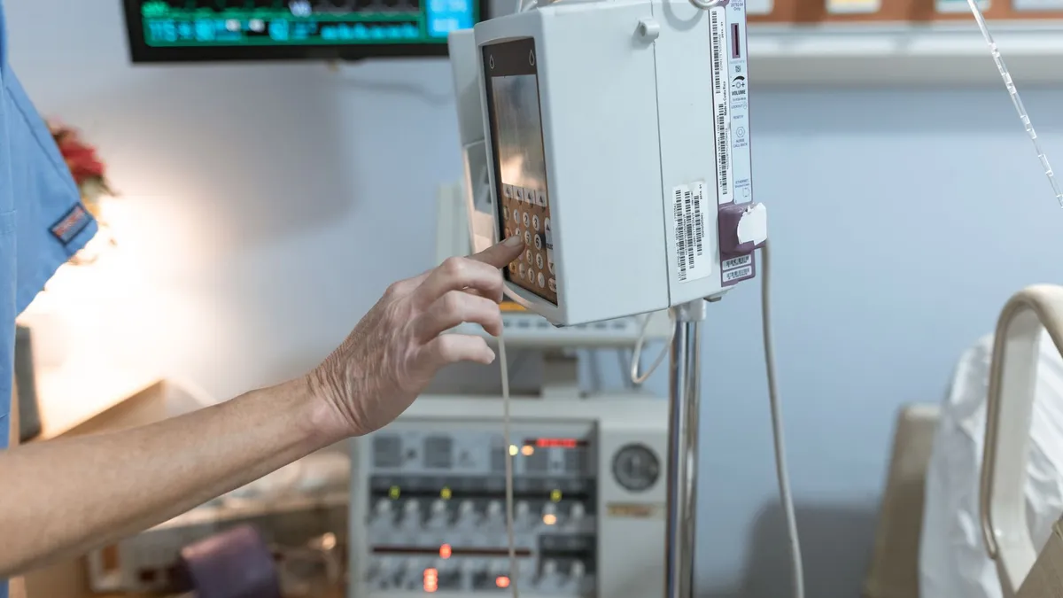 A healthcare worker operates a modern infusion pump in a hospital setting, ensuring precise medication delivery.