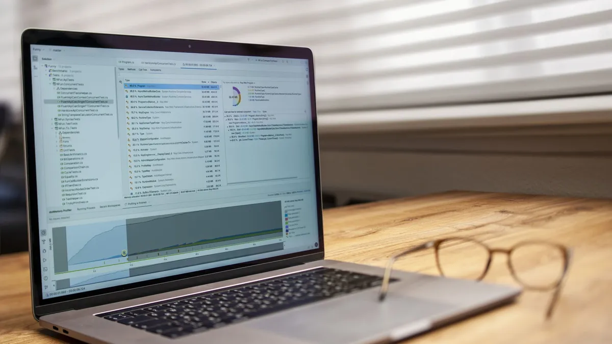 Modern laptop on a wooden desk displaying analytical software with eyeglasses nearby, indoor shot.