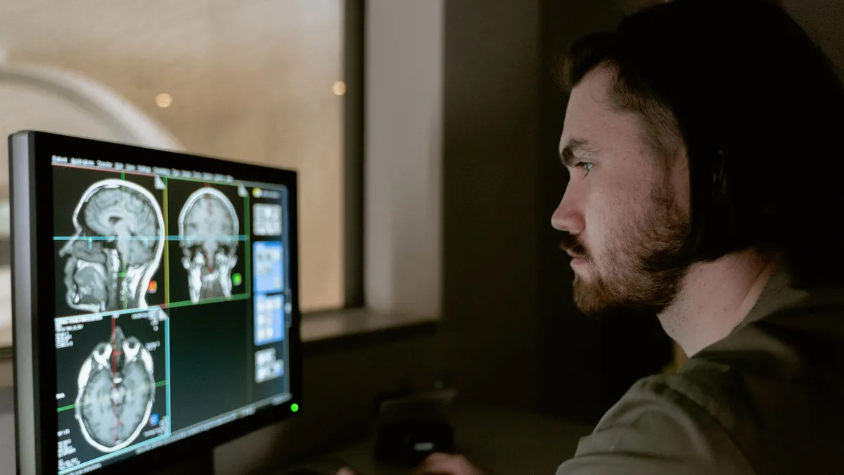 Radiologist examining a CT scan on a monitor in a medical facility.