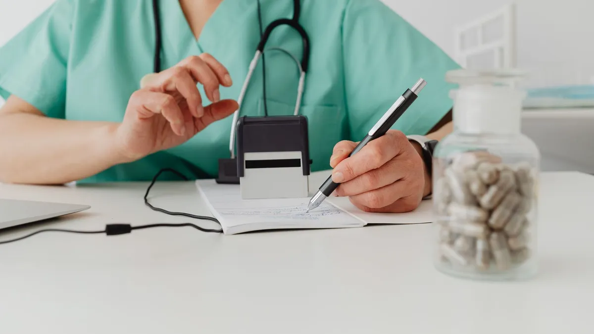 A medical professional writing a prescription in a clinical setting.
