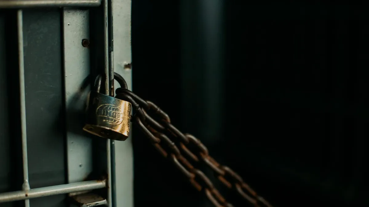An artistic close-up photo of a faded padlock securing a chain on a metal door, symbolizing security.