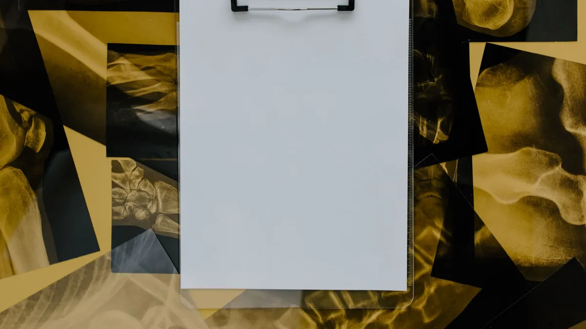 Top view of a blank clipboard on a background of various skeletal x-ray images, ideal for medical themes.