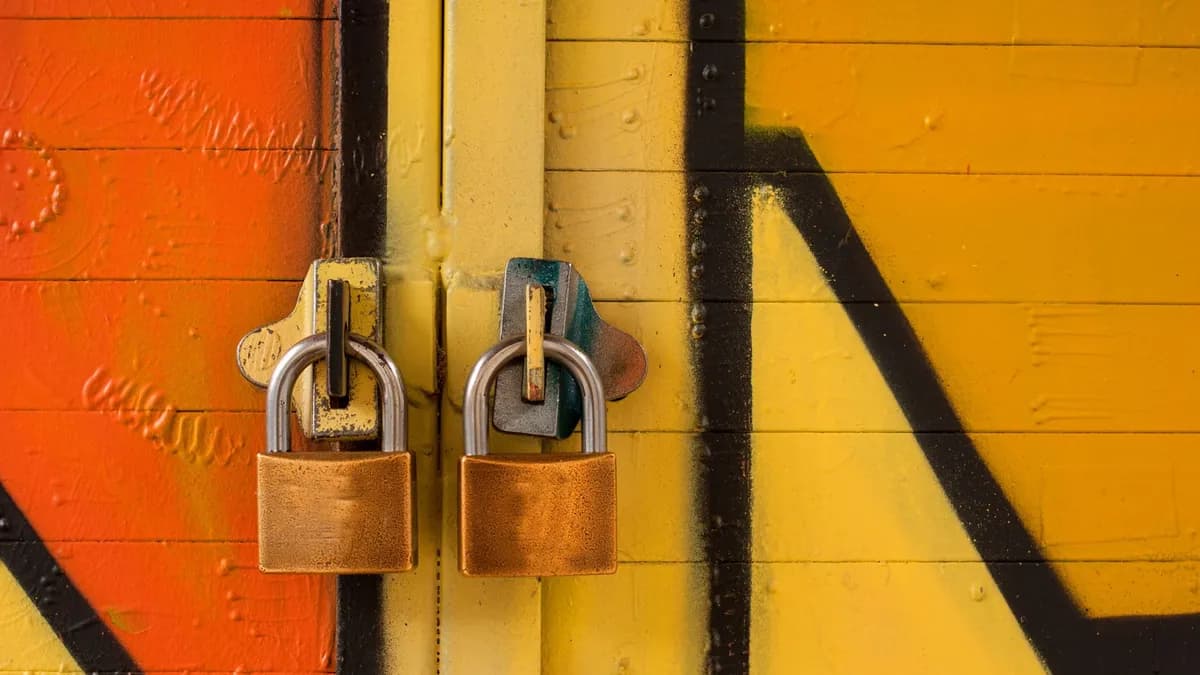 Close-up of two brass padlocks securing a vibrant graffiti-painted door, symbolizing security.