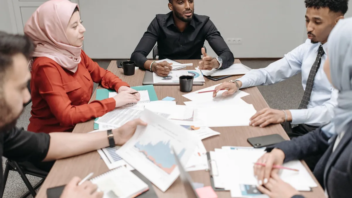 Multicultural team discussing business reports around a table indoors.