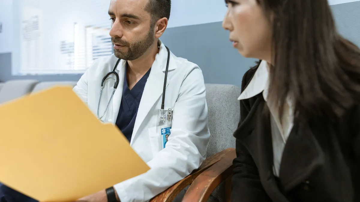 Doctor discusses health records with a patient in a clinical setting.