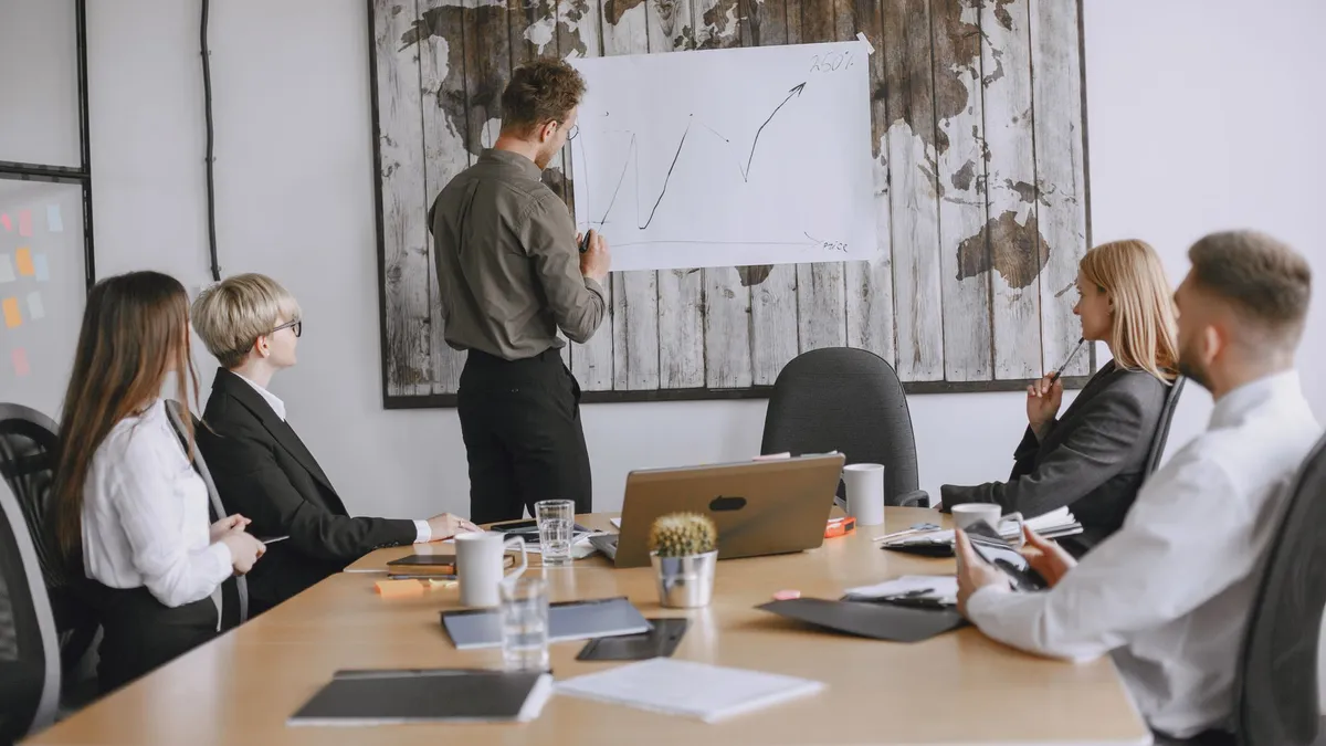 Group of business professionals discussing strategies with growth chart in conference room.