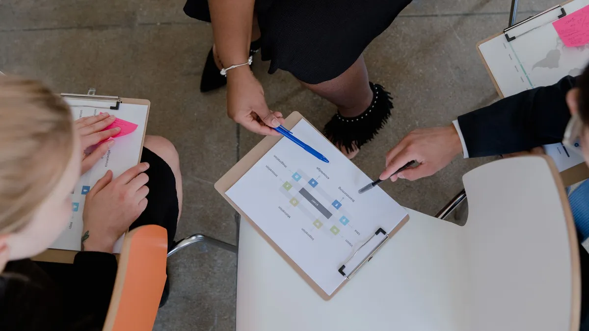 Top view of colleagues discussing and brainstorming ideas with clipboards in a meeting.