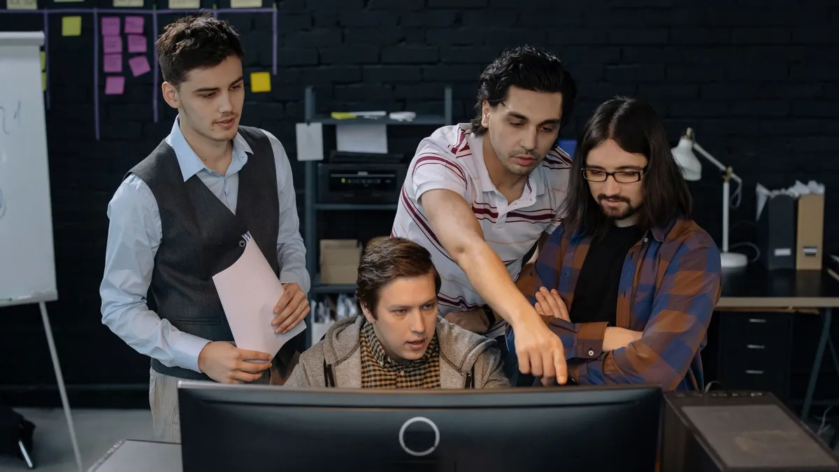 Group of professionals discussing a project at a computer in a modern office environment.