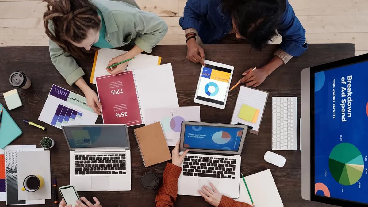 A diverse team collaborating on digital marketing strategies at a desk, using laptops and tablets.