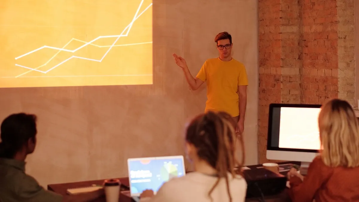 A young man gives a presentation on data analysis in a modern office setting.