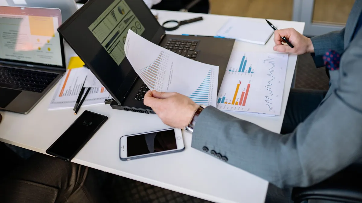 Professionals analyzing charts and graphs on laptops during a business meeting.