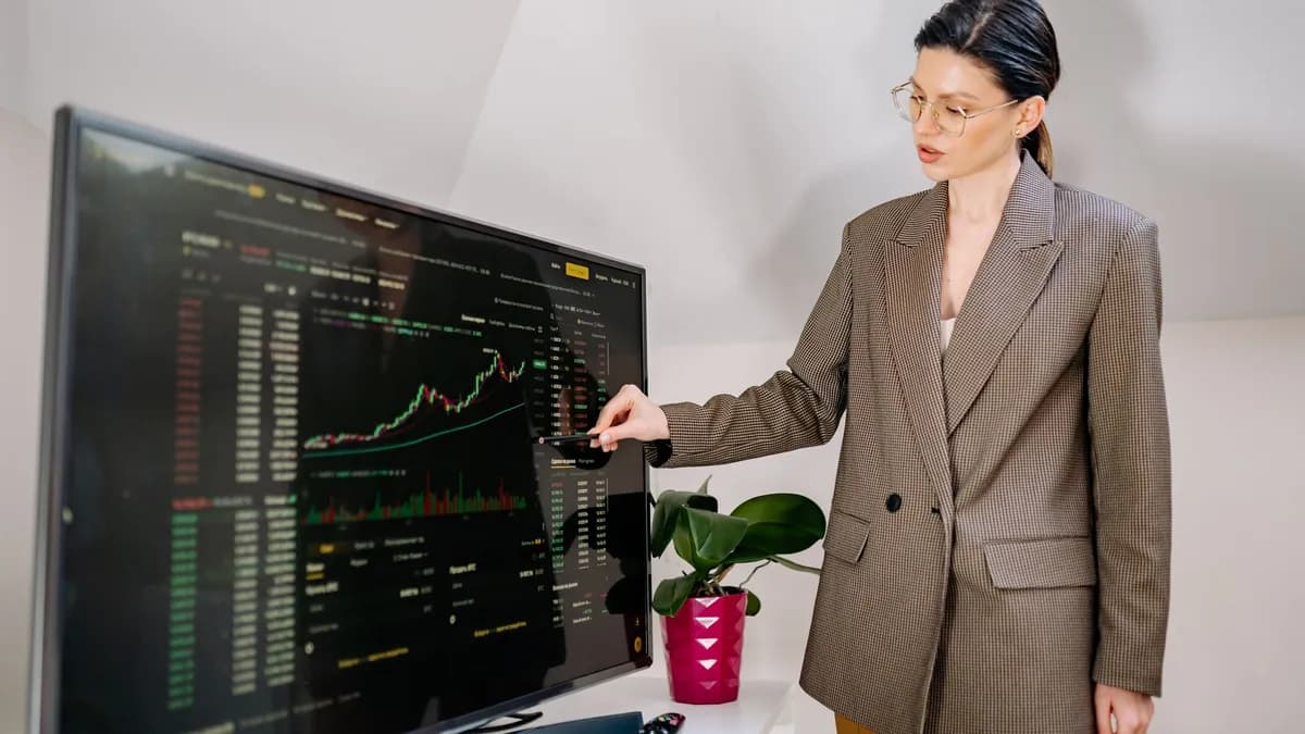 Businesswoman using stylus to highlight stock data on a monitor in office.