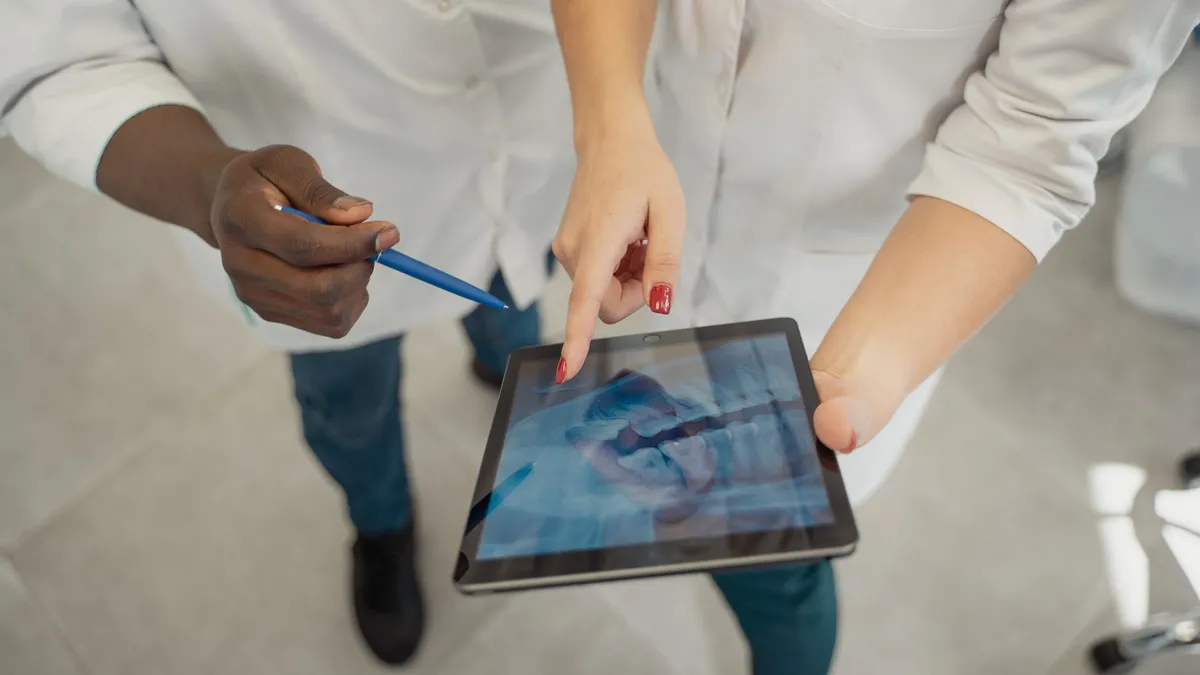Two medical professionals analyzing a dental x-ray on a tablet. Collaborative healthcare setting.