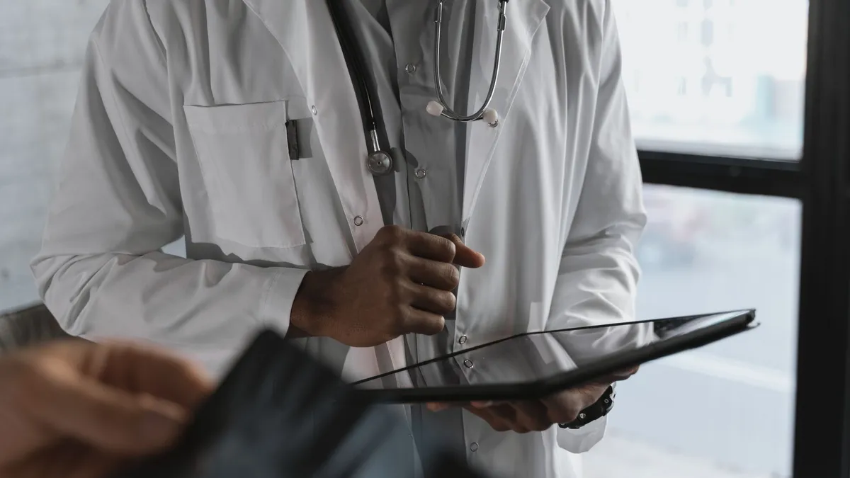 A professional medical practitioner holding a tablet, focused on work in a clinical setting.