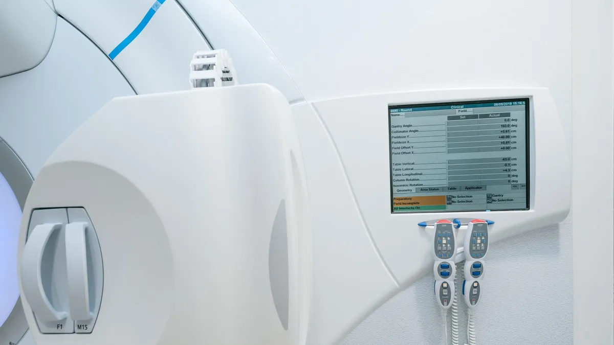 Close-up of advanced radiotherapy equipment with control panel and screen. High-tech medical tech.