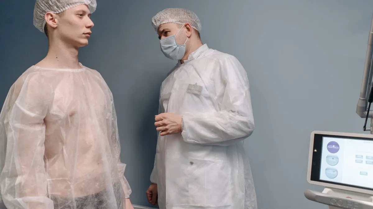 A doctor examines a patient in a clinic wearing medical gowns for a mole pathology evaluation.