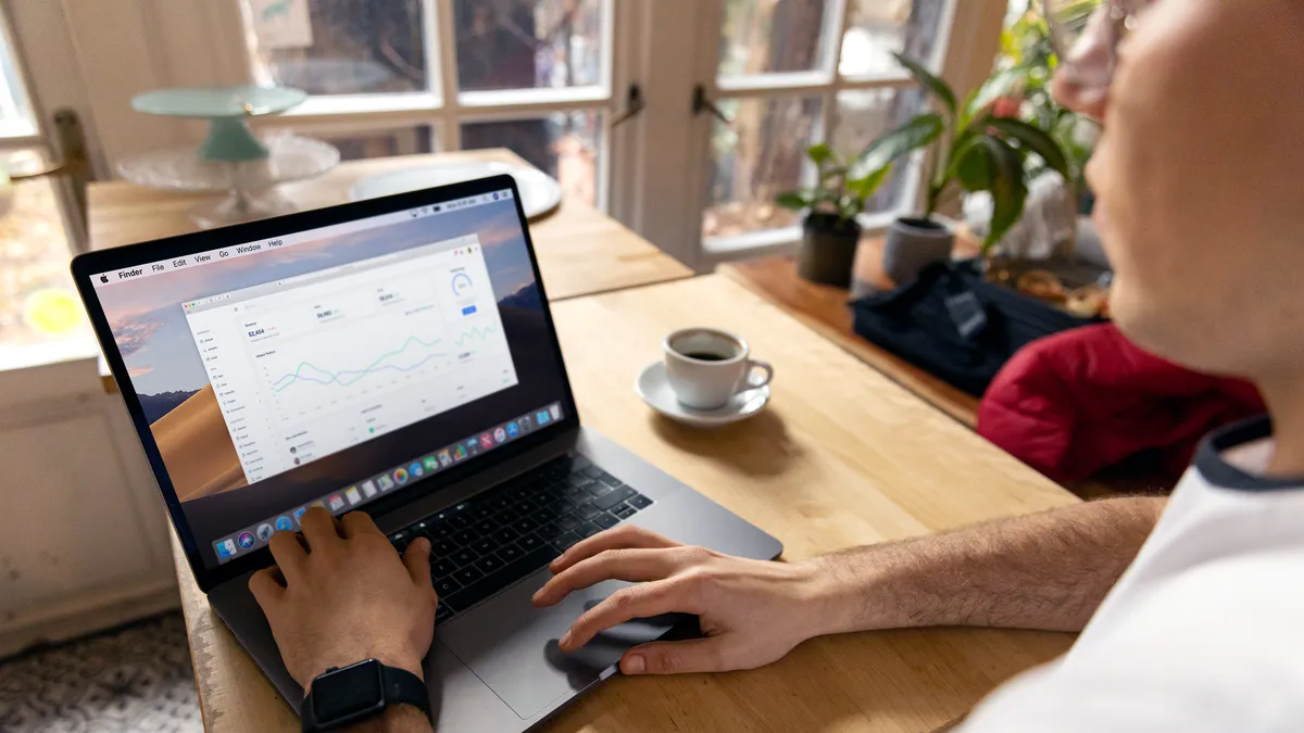 A person working on a laptop with business analytics displayed, showcasing a remote work setup in a cozy environment.