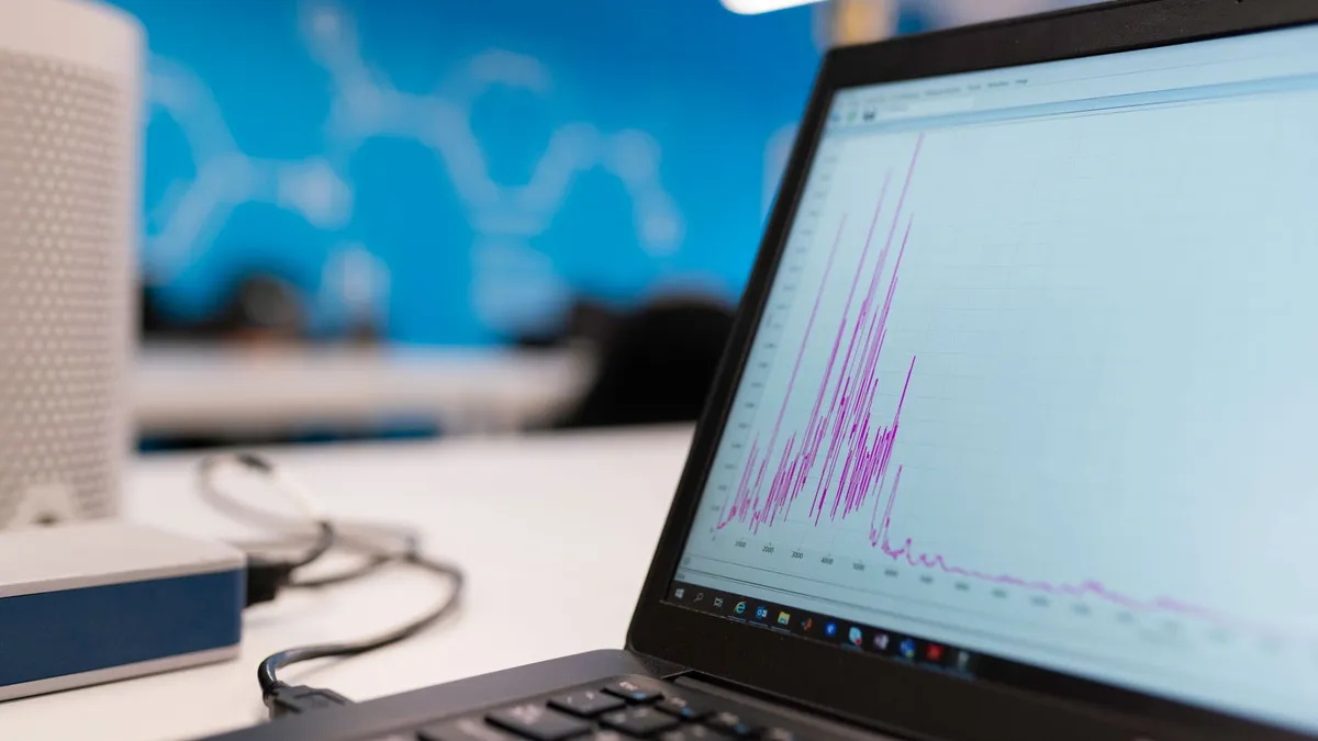 Laptop displaying data analytics graph in a modern office setting, symbolizing growth and technology.