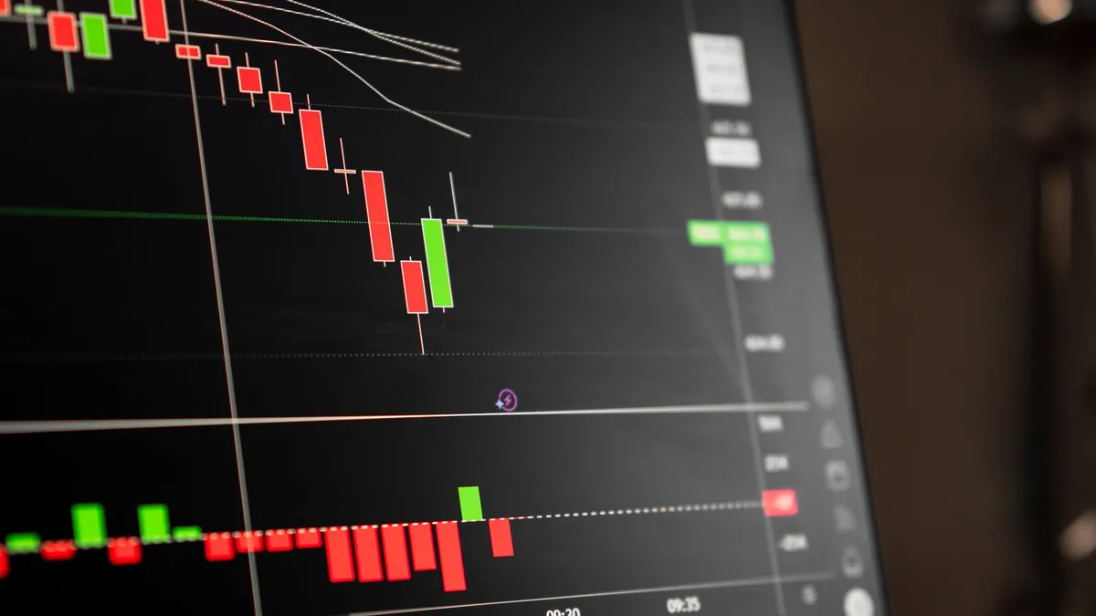 A close-up of a digital screen showing stock market candlestick chart data.