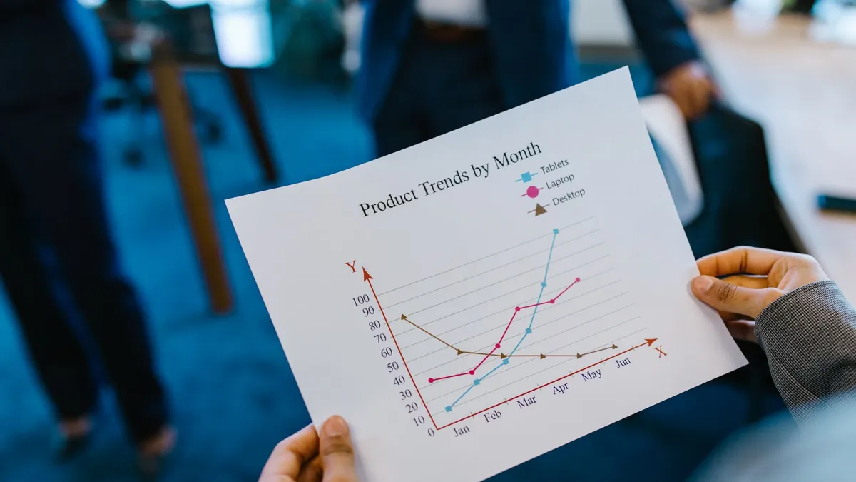 Close-up of hands holding a product trend chart in a corporate office setting.