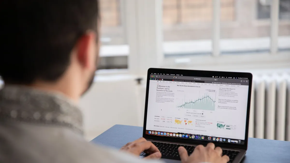 A person working on a laptop analyzing financial data in a bright indoor setting.