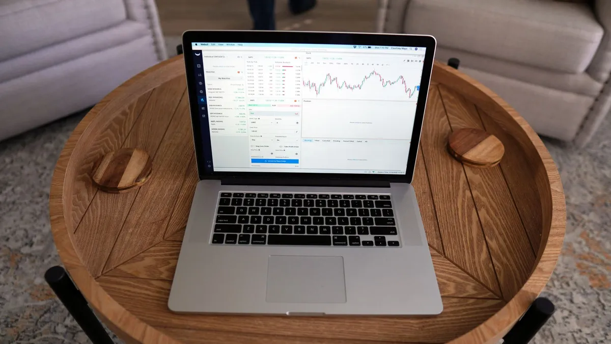 Close-up of a laptop displaying trading charts on a stylish wooden table, ideal for financial themes.