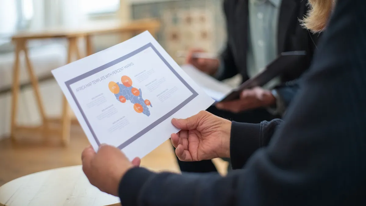 Three professionals discussing a data presentation in an office setting.