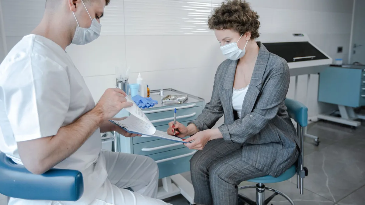 A doctor and patient wearing face masks during a consultation in a modern medical office.