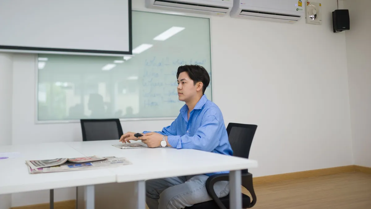 Businessman sits alone in modern office meeting room using technology.