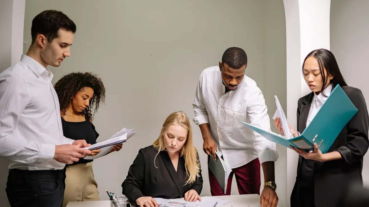 Diverse team working together in an office setting, reviewing documents and collaborating on projects.