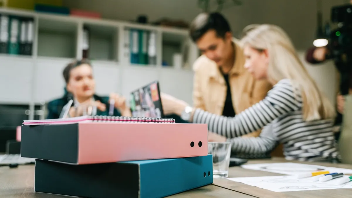 Focused group discussing strategy in an office with binders and modern decor.